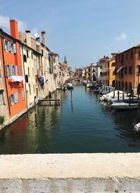 Canal amidst buildings against sky in city