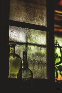 Close-up of glass of bottles on window