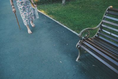 Low section of woman walking with cane on footpath