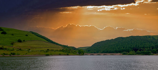 Scenic view of river against sky at sunset