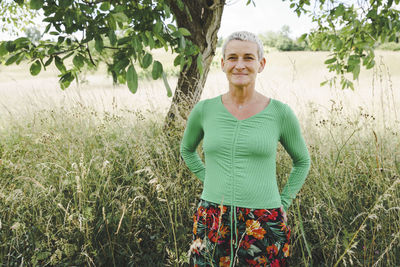 Portrait of young woman standing against plants