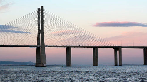 Bridge over sea against sky during sunset