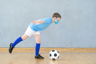 Side view of boy playing soccer ball