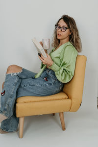 Young woman sitting on sofa at home - dreamy photoshoot - reading a book