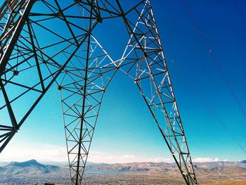 Low angle view of electricity pylon against blue sky