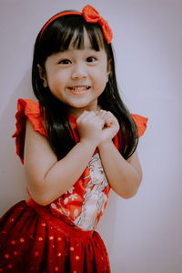 Portrait of smiling girl standing against gray background