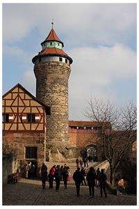 People in front of tower against sky in city