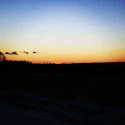 Scenic view of silhouette field against clear sky during sunset