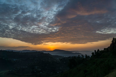 Scenic view of landscape against dramatic sky during sunset