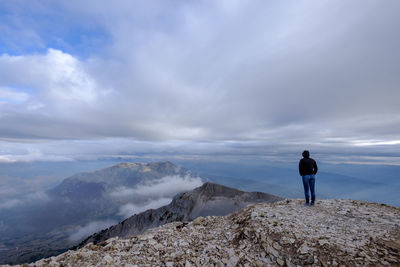 Rear view of man standing on mountain against sky