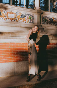 Portrait of woman standing against brick wall