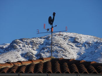 Low angle view of snowcapped mountains against clear blue sky