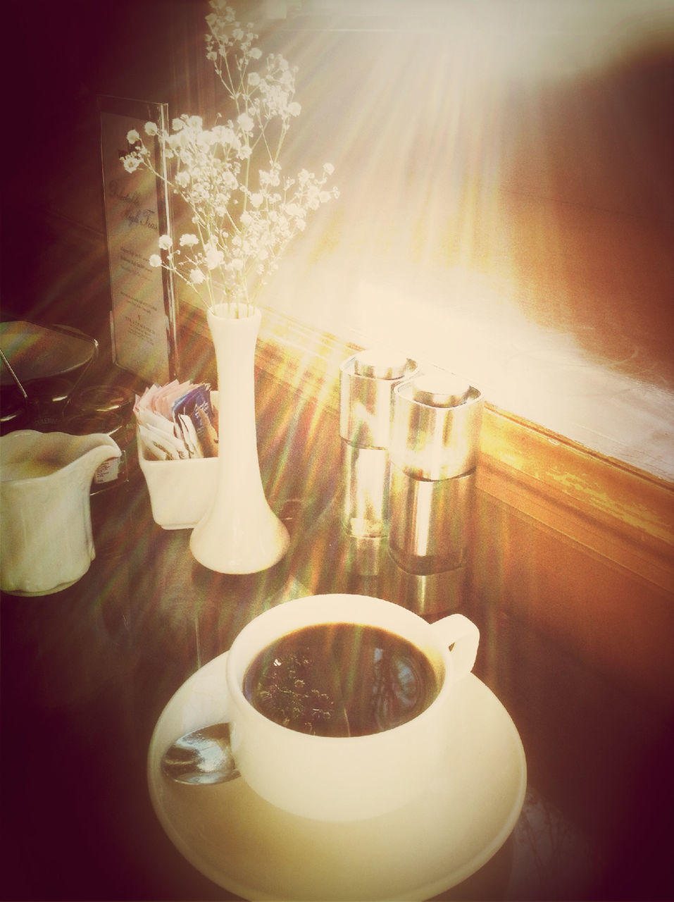 indoors, table, coffee cup, still life, drink, home interior, food and drink, coffee - drink, saucer, cup, high angle view, close-up, spoon, refreshment, no people, freshness, chair, vase, coffee, sunlight