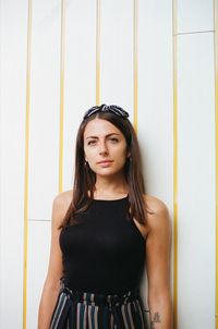 Portrait of a beautiful young woman standing against wall