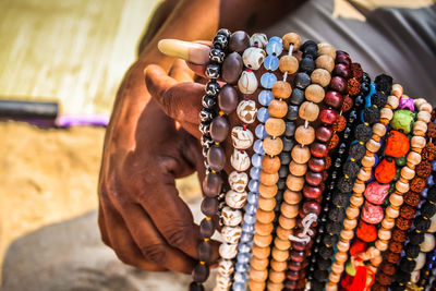 Cropped hands of man selling bead necklaces at beach