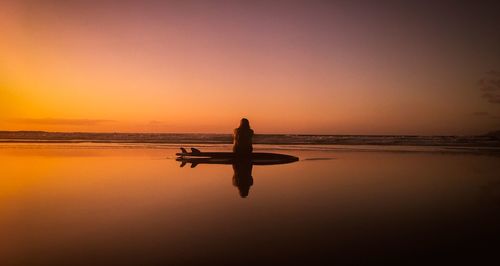 Silhouette woman at beach against sky during sunset