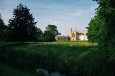 Lake and trees with university in background against sky