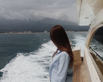 Rear view of woman standing on boat sailing in sea