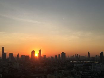 Silhouette buildings against sky during sunrise