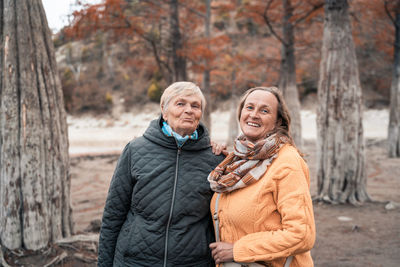 Happy friends standing against trees