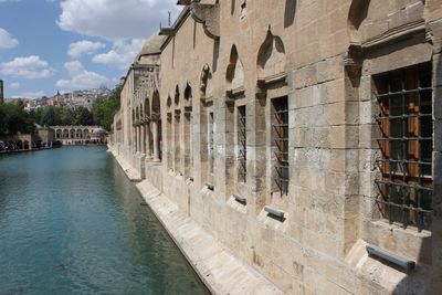 Buildings by canal against sky in city