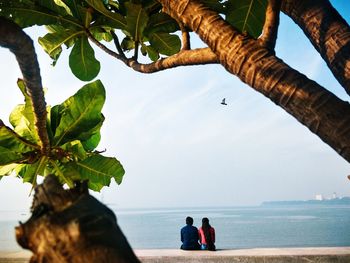 Rear view of people on beach against sky