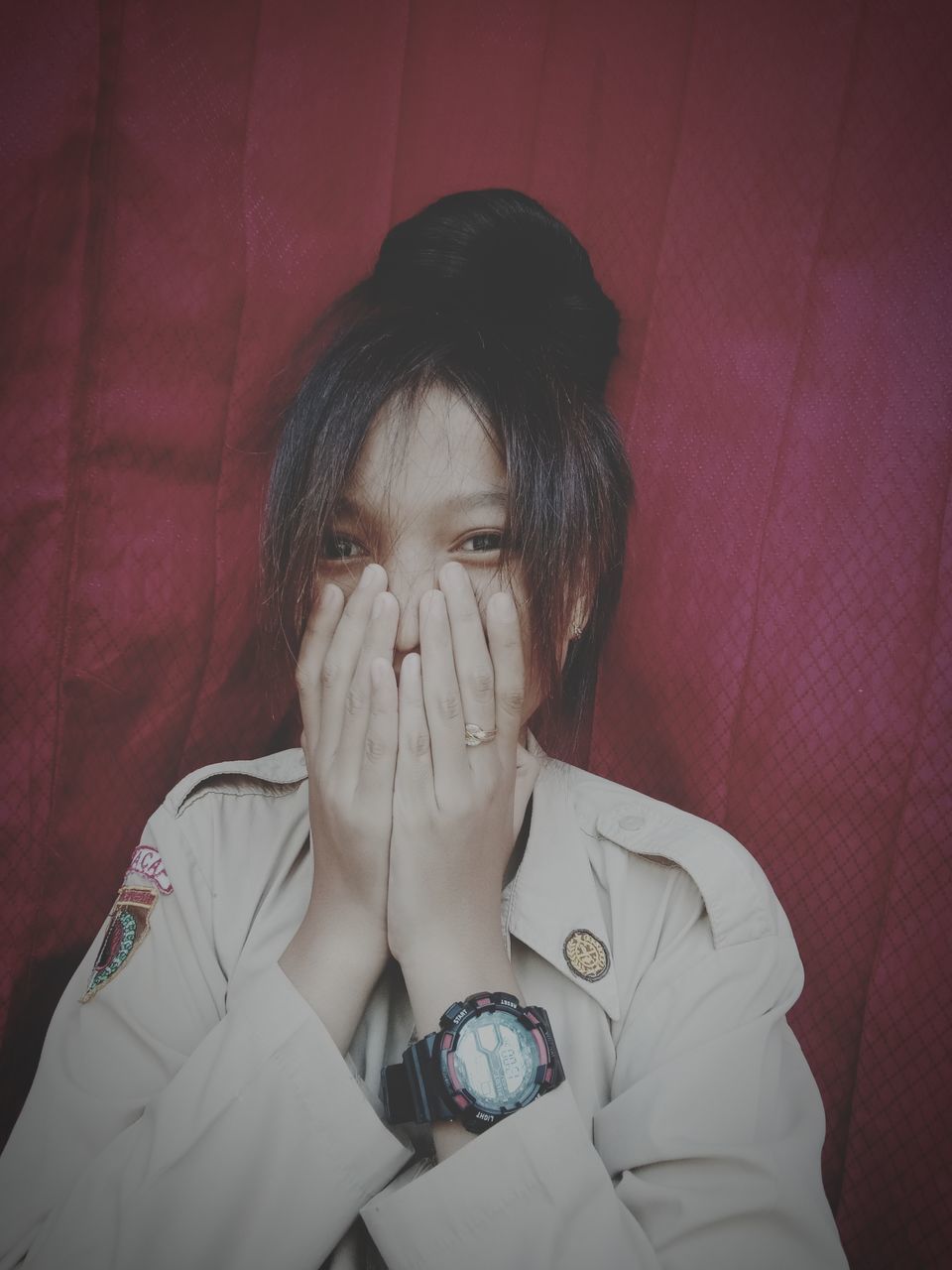 real people, front view, child, one person, childhood, indoors, portrait, headshot, lifestyles, girls, innocence, clothing, casual clothing, leisure activity, wall - building feature, cute, covering, hands covering mouth, human face