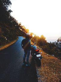 Rear view of man riding motorcycle on road against sky