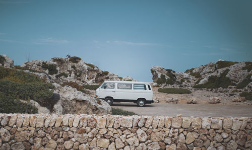 Car on rocks by road against sky