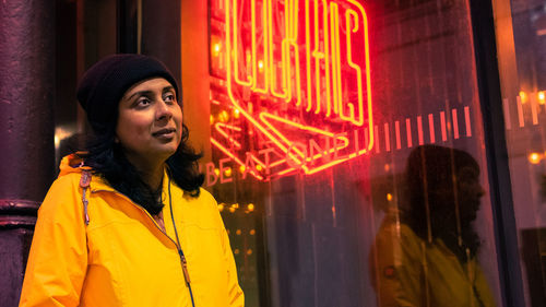 Portrait of man standing against illuminated window at night