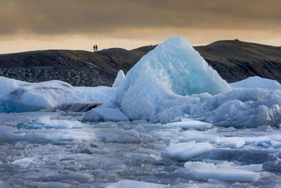 Icebergs in sea against sky during sunset