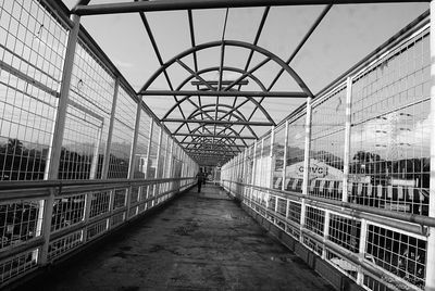 People walking on bridge against cloudy sky