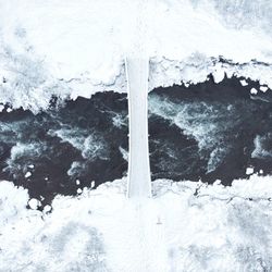 Aerial view of river amidst snow covered field