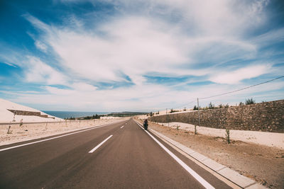 Road leading towards highway against sky