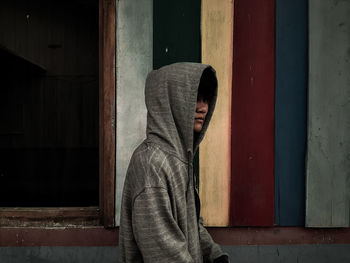 Portrait of man standing against window