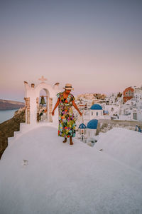 Rear view of woman standing outside building against clear sky