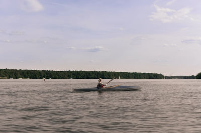 Woman sitting on boat in sea against sky