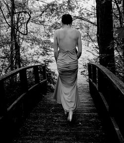 Rear view of woman walking on wooden bridge 
