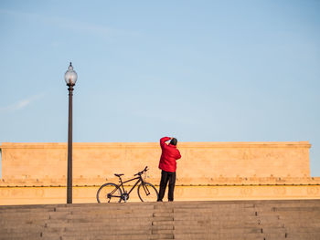 Rear view of man riding bicycle against sky