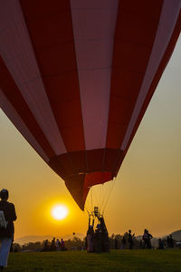 Hot air balloon amidst people against sky during sunset