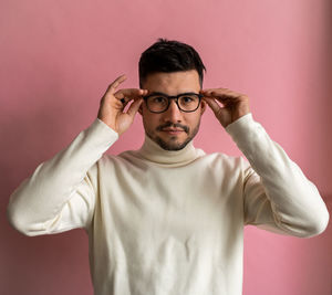 Portrait of bearded man trying on eyeglasses and looking camera attentively while posing