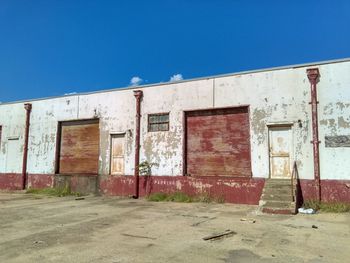 Facade of abandoned house against clear blue sky, truck parking only