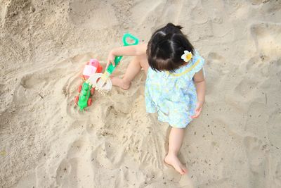 High angle view of girl playing on sand at beach