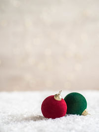 Christmas vilvet ball in foreground in artificial snow and  blurred background with glowing garland.