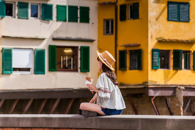 Full length of woman sitting outside building