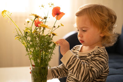 Baby girl, toddler, infant touching looking at field wild flowers bouquet.early development