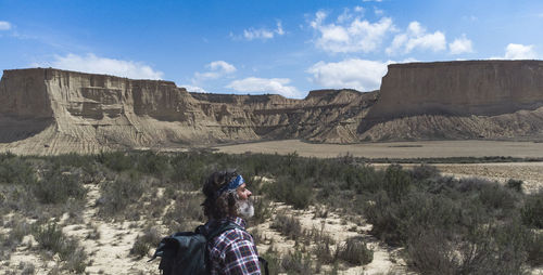 Rear view of man standing on mountain against sky