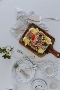 Swedish sandwich cake with shrimps, cheese, ham and eggs on wooden board at table