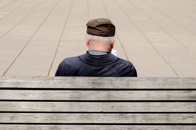 Rear view of senior man sitting on wooden bench