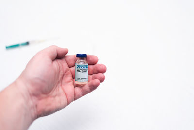 Close-up of hand holding camera over white background